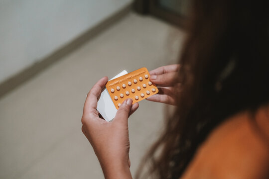 Back view of the hands of a young woman holding a pack of birth control pills. Contraceptive pills. Birth control. Childfree.