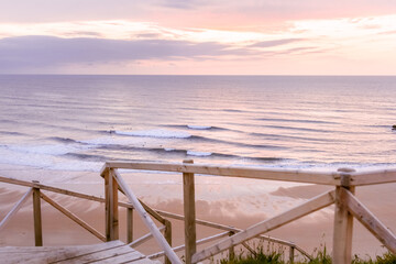 Serene beach scene with gentle waves and wooden staircase