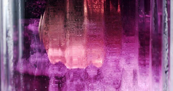 Super slow motion macro of bartender is mixing fresh aromatic elegant alcoholic cocktail in transparent glass ice cubes before to serve it to customer in bar or disco club at 1000 fps.