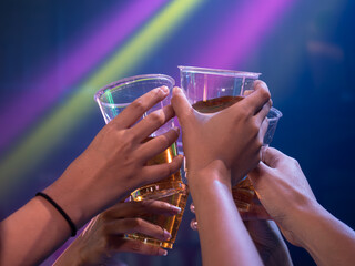 People raise a toast and make cheers with plastic glasses of champagne in the nightclub. Toast Beverage Concept..
