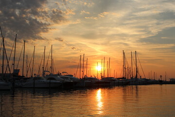 calm orange sunset in the harbor during holiday with lots of sailboats and yachts