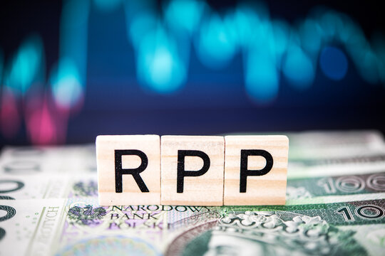 Wooden Blocks Spelling 'RPP' on Polish Złoty Banknotes with Defocused Blue Lights in the Background