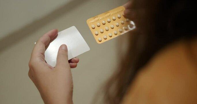 Back view of the hands of a young woman holding a pack of birth control pills. Contraceptive pills. Birth control. Childfree.