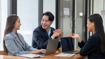 Business team discussing project in office meeting, collaborating with laptops and documents for strategy planning.