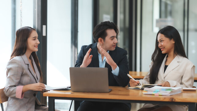 Business meeting with three professional colleagues discussing and brainstorming ideas in a modern office setting.