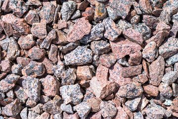Natural granite chips, crushed stone close-up, natural background, top view.