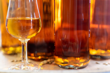 Glass of whisky glencairn close-up on blurred background of whisky bottles on wooden cask