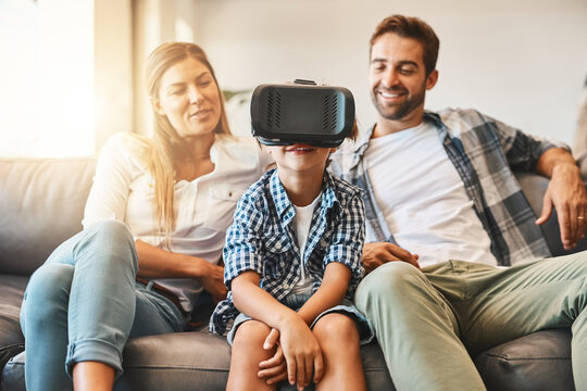 Virtual reality, family and child on sofa with headset for futuristic, digital interaction or learning in home. Lens flare, metaverse and young kid for simulation, curiosity or education video game