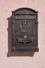 Metal mailbox on a plastered pink wall