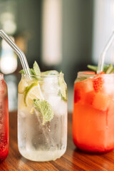 Fruit drinks with ice in glass glasses and straws on a wooden table.