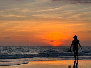 Fototapeta premium person walking on the beach at sunset