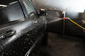 Washing auto at self service car wash. Cleaning and washing car under high pressure, which helps effectively remove dirt and dust.