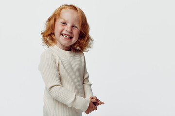 Happy redhaired girl in white sweater smiling on white background, portrait of joyful child beauty...