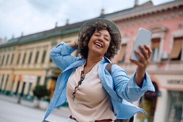 Naklejka premium Happy tourist having fun while talking selfie with her cell phone in city.