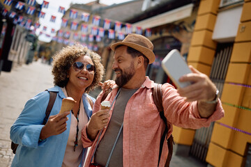 Happy couple of travelers taking selfie while eating ice cream.