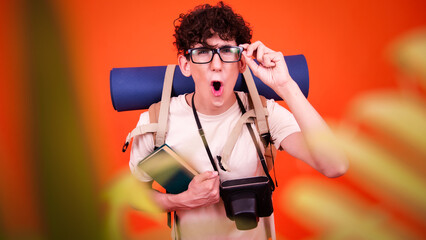 Vacations and holidays. Funny lost tourist with a backpack. Orange background.