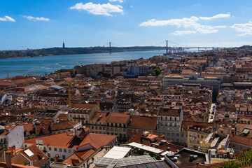 Fototapeta premium Suspension bridge Ponte 25 de Abril in Lisbon, Portugal. View of colourful facades and The 25th April Bridge over river Tagus (Tejo).