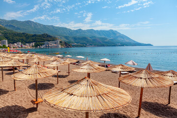 Becici beach in Montenegro. Beach scene with colorful umbrellas and lounge chairs on the sand