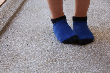 Feet of kid standing on concrete floor. child wear navy and indigo blue socks .