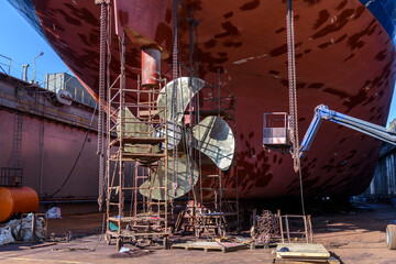 Cargo vessel in dry dock on ship repairing yard. Variable pitch propeller and rudder. Welder...