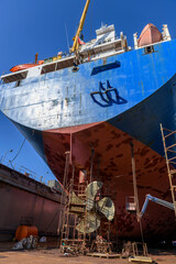 Cargo vessel in dry dock on ship repairing yard. Variable pitch propeller and rudder. Welder...