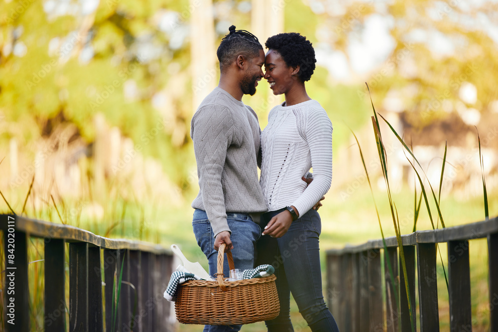 Poster Black couple, love and picnic at park with basket for anniversary date, honeymoon celebration and romance with smile. People, embrace and happy on bridge in nature with support, care and holiday fun