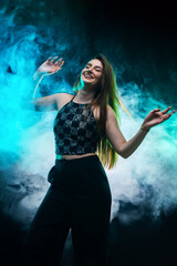 Happy woman dancing with blue smoke background in stylish outfit