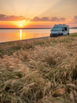 sunrise on the coast with view to alone white camper home on grass meadow with copy space