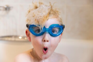 A young boy having fun in the bath wearing swimming goggles