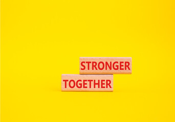 Stronger together symbol. Wooden blocks with words Stronger together. Beautiful yellow background. Stronger together concept. Copy space.