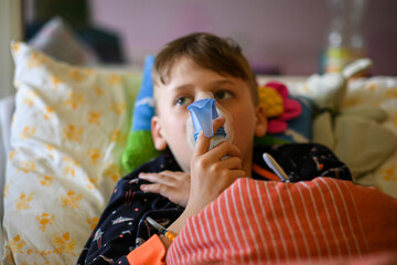 Child patient takes medication via an inhaler while sitting in a hospital bed