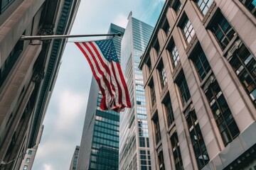 US flag flying in city street amidst towering buildings
