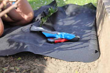 Laying an anti-weed mat in the garden together with paving stones and decorative pebbles