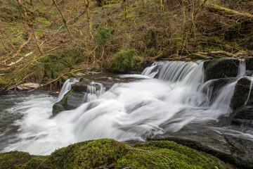 Long exposure of a waterfall flowing through the woods at Watersmeet in Exmoor National Park