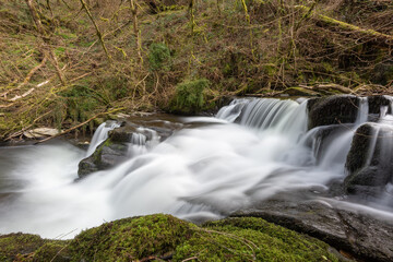 Long exposure of a waterfall flowing through the woods at Watersmeet in Exmoor National Park