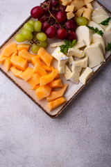 Cheese plate with different cheese, grapes and melon.