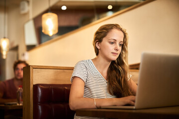 Woman, serious and research at coffee shop with laptop as university student for elearning or...