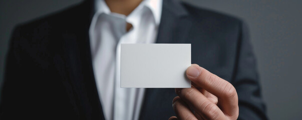 Businessman holding a blank white business card, close-up view. Corporate identity and networking concept