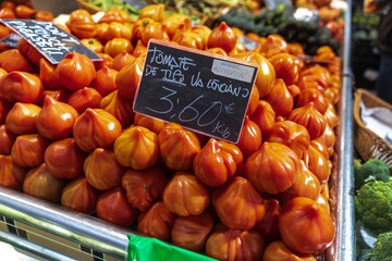 Early variety tomatoes Rosa for sale at the market in a box. One tomato is cut into two parts for display. Square frame