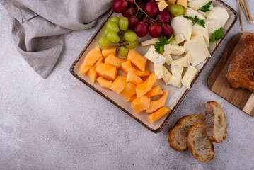 Cheese plate with different cheese, grapes and melon.