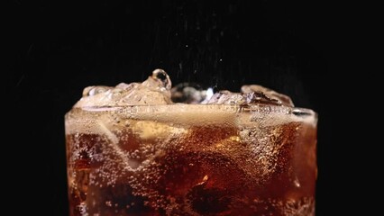 Closeup of pouring cola drink with ice cubes. Fizzing cola with ice in glass. Refreshing tasty cola drink. - Powered by Adobe