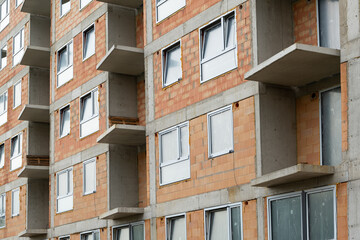 Obraz premium red clay ceramic thermo brick multi-story building before insulation and cladding. New windows installed, reflecting the real estate market.