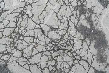damaged surface of old, cracked asphalt shows the condition of the road with visible cracks.
