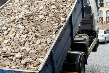 Self Loading container with heavy construction debris, including broken bricks, picked up by truck....