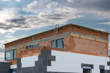 Fototapeta premium The new house construction process involves insulating the walls with modern thermal insulation materials. Exterior covering is applied at the construction site.