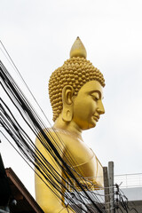 The Giant Buddah of Bangkok seen between cables, buldings and houses in the city of Bangkok