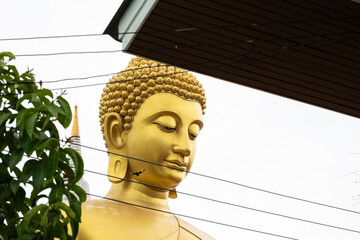 The Giant Buddah of Bangkok seen between cables, buldings and houses in the city of Bangkok