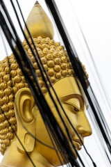 The Giant Buddah of Bangkok seen between cables, buldings and houses in the city of Bangkok
