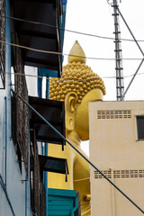The Giant Buddah of Bangkok seen between cables, buldings and houses in the city of Bangkok