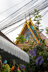 The Giant Buddah of Bangkok seen between cables, buldings and houses in the city of Bangkok